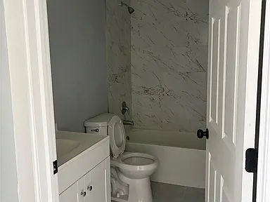 Bathroom with vanity, toilet, and tub-shower combination