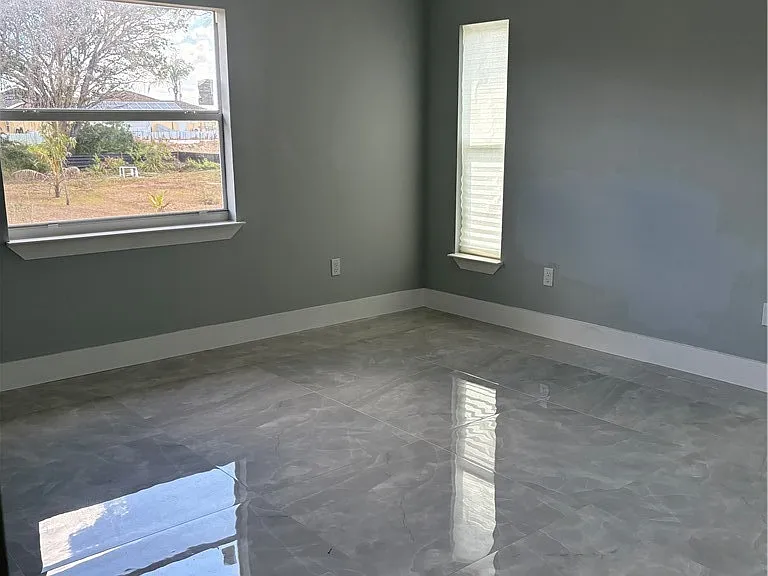 Bedroom with gray walls, two windows, and polished tile flooring