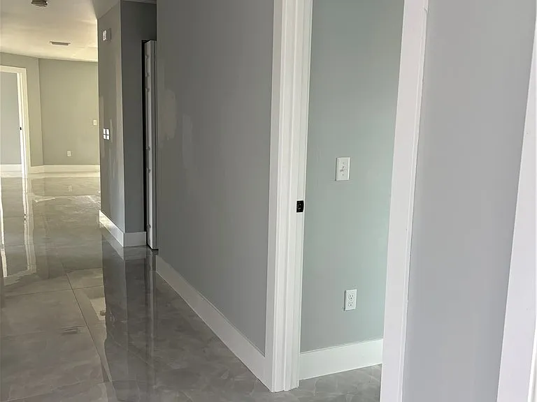 Interior hallway with gray walls, white trim, and polished tile flooring