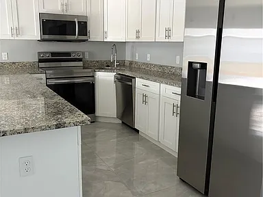 Kitchen with white cabinets, granite counters, and stainless steel appliances